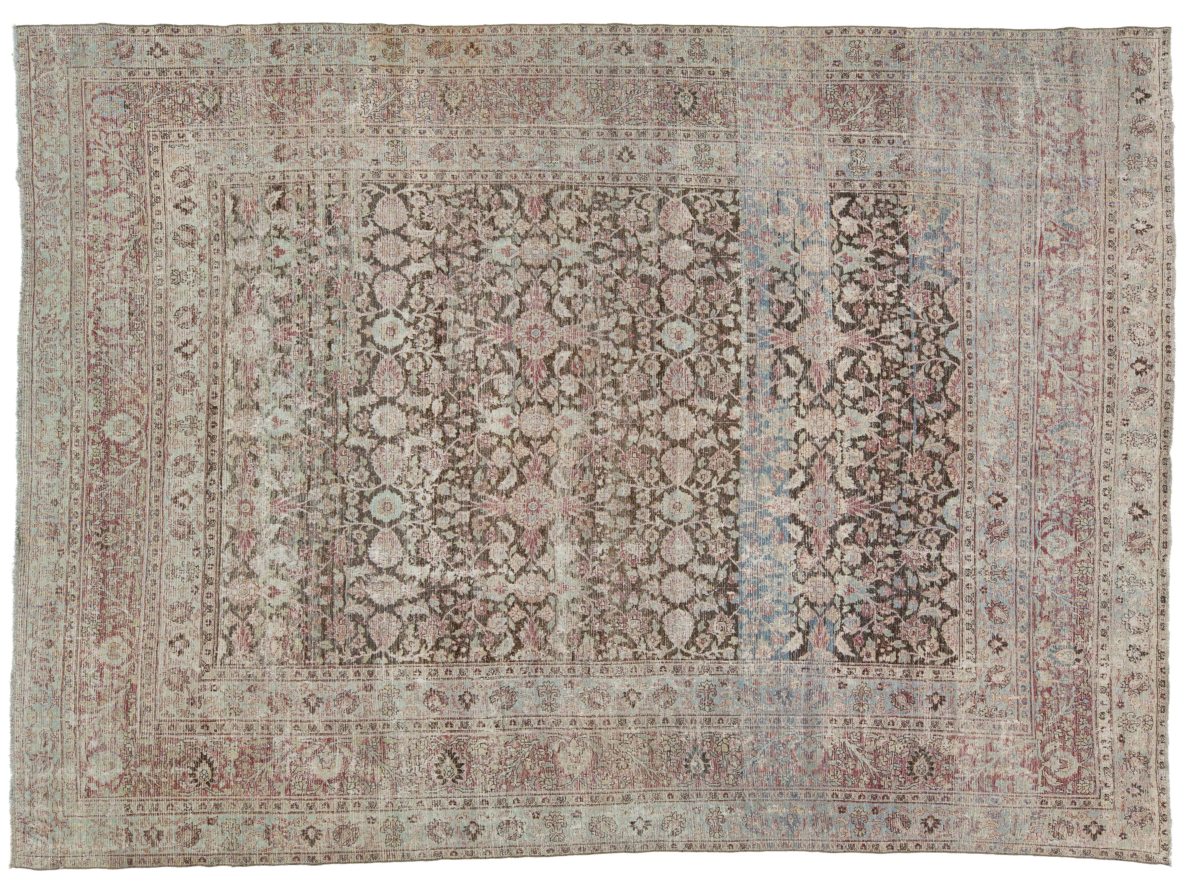 An antique-style oriental rug with a faded floral pattern, featuring a central field and multiple borders in muted tones of dusty pink, beige, gray, and light blue.