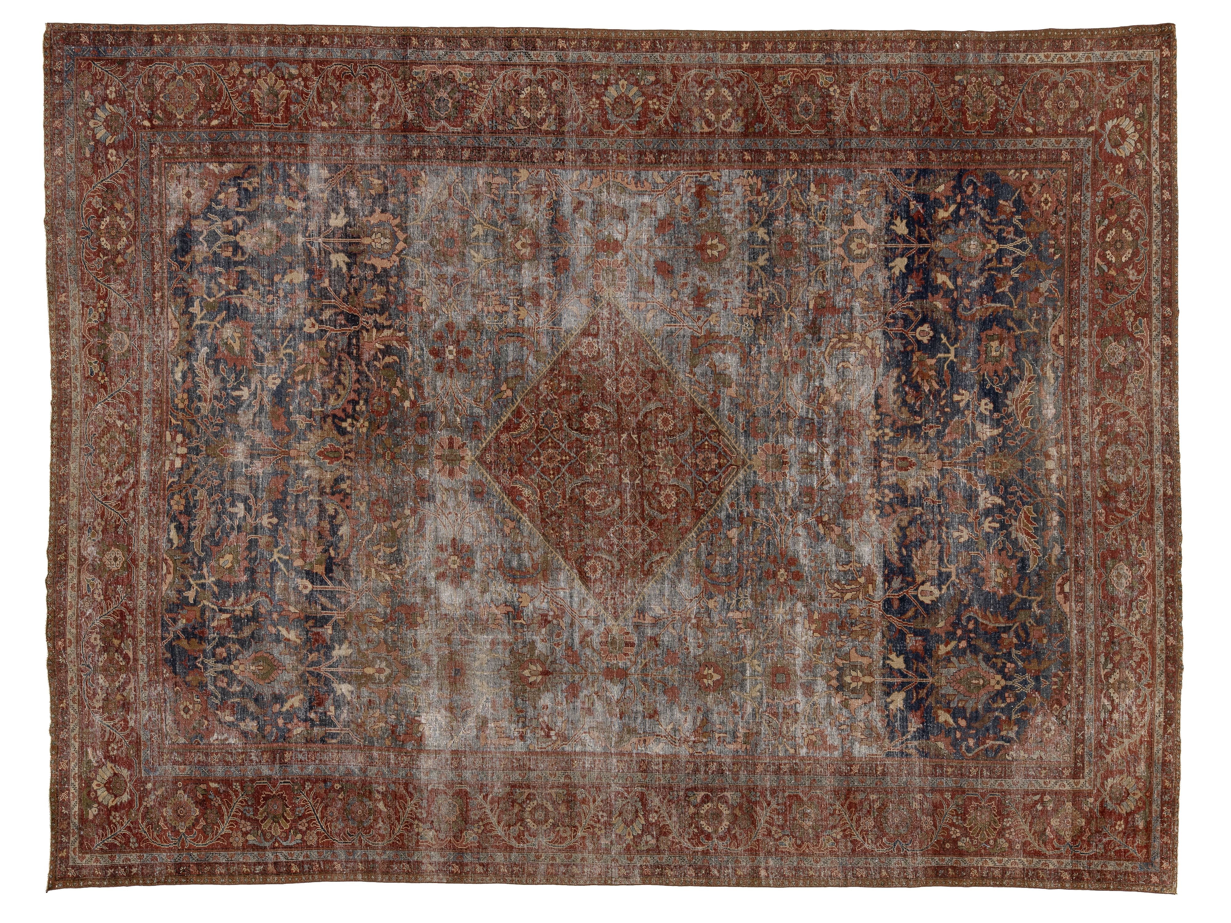 A distressed vintage-style oriental rug with a central diamond medallion, featuring a dusty blue-gray field, dark navy blue side panels, and a rust-brown border.