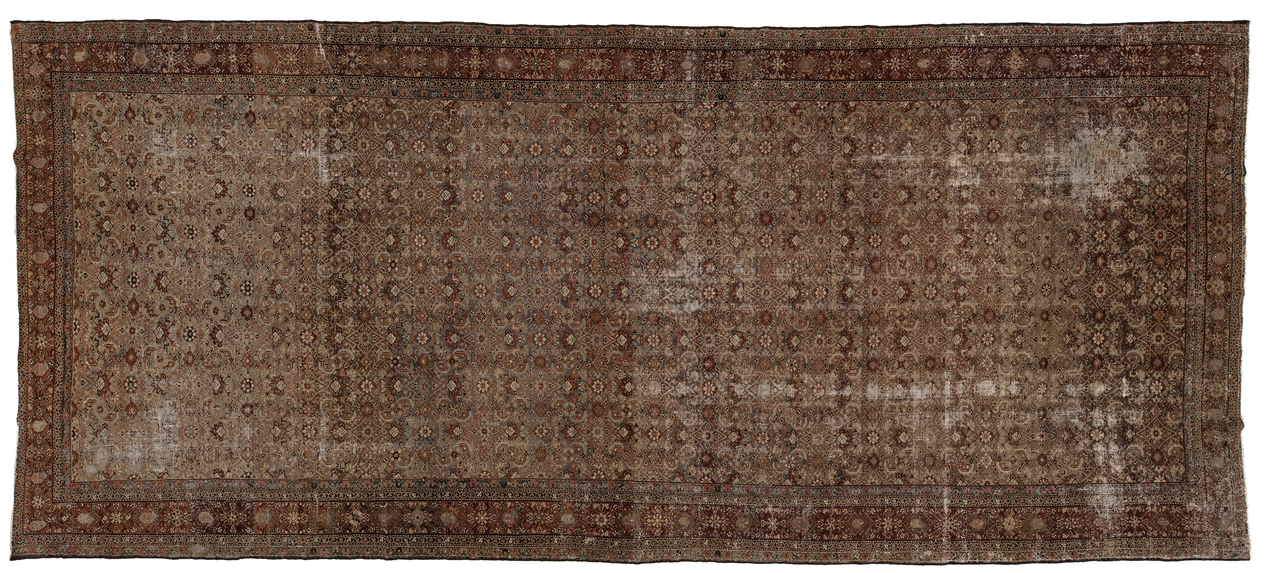A rectangular vintage-style area rug with an intricate, distressed geometric pattern in shades of brown, beige, and muted red, shown flat against a white background.
