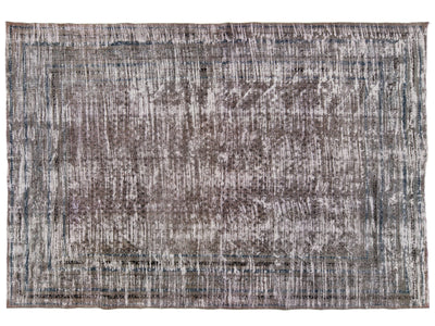 A rectangular area rug with a distressed, antique-style pattern in shades of gray, brown, and muted blue, shown flat against a white background.