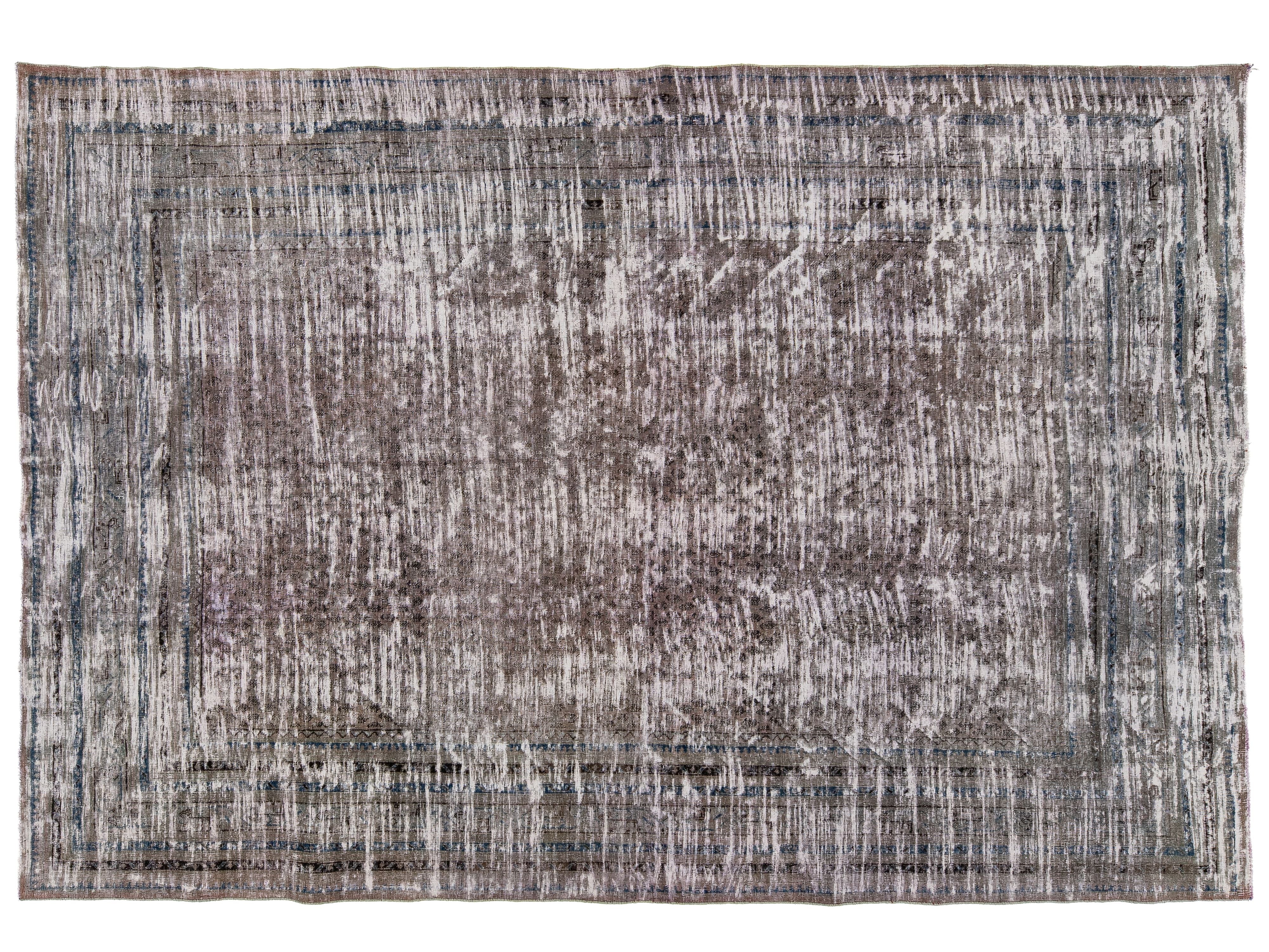 A rectangular area rug with a distressed, antique-style pattern in shades of gray, brown, and muted blue, shown flat against a white background.