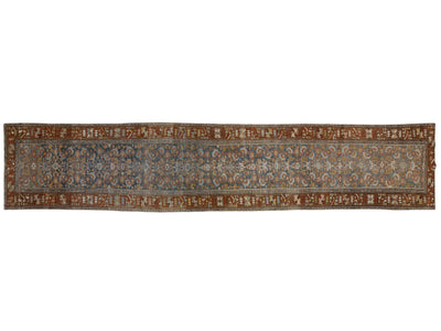 A long, narrow traditional oriental rug with an intricate floral pattern in muted blue, rust red, beige, and brown tones.