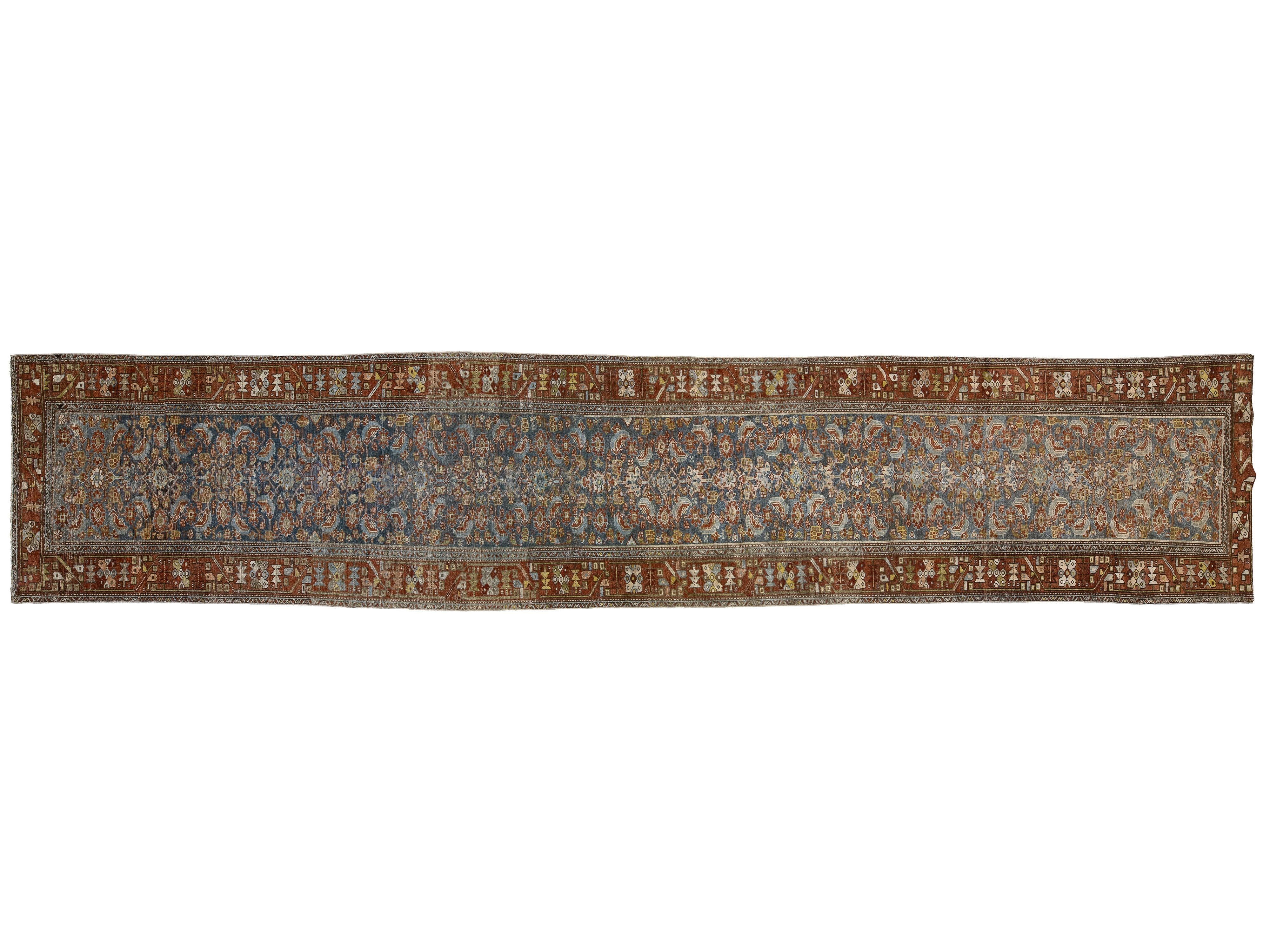 A long, narrow traditional oriental rug with an intricate floral pattern in muted blue, rust red, beige, and brown tones.