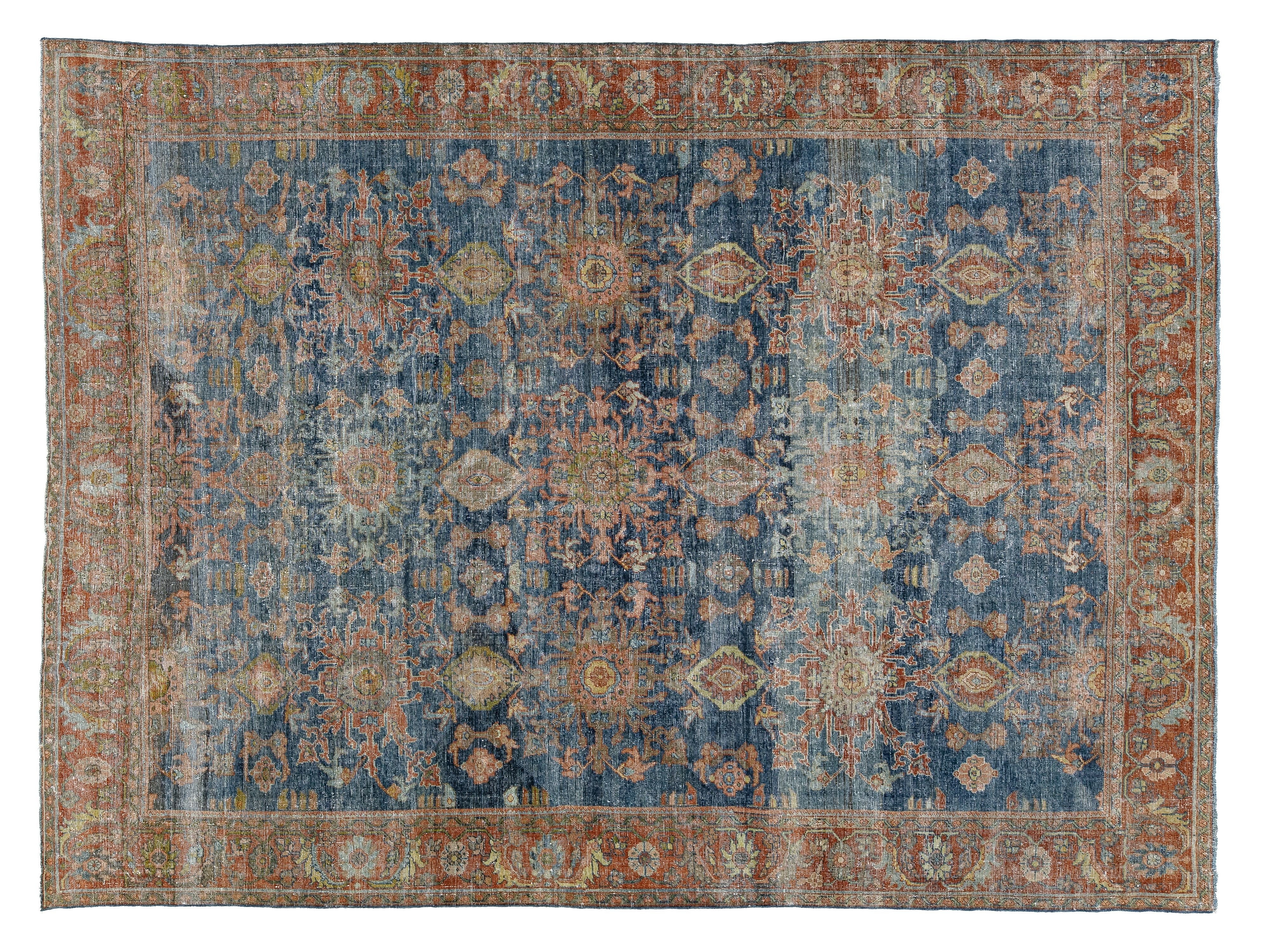 A distressed traditional area rug with an intricate floral pattern, featuring a dominant blue field, rust-orange borders, and beige accents.
