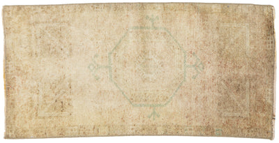 A rectangular vintage-style rug with a distressed, faded appearance. The rug features a muted central octagonal medallion and corner motifs in a pale sage green on a heavily worn, sandy beige background.