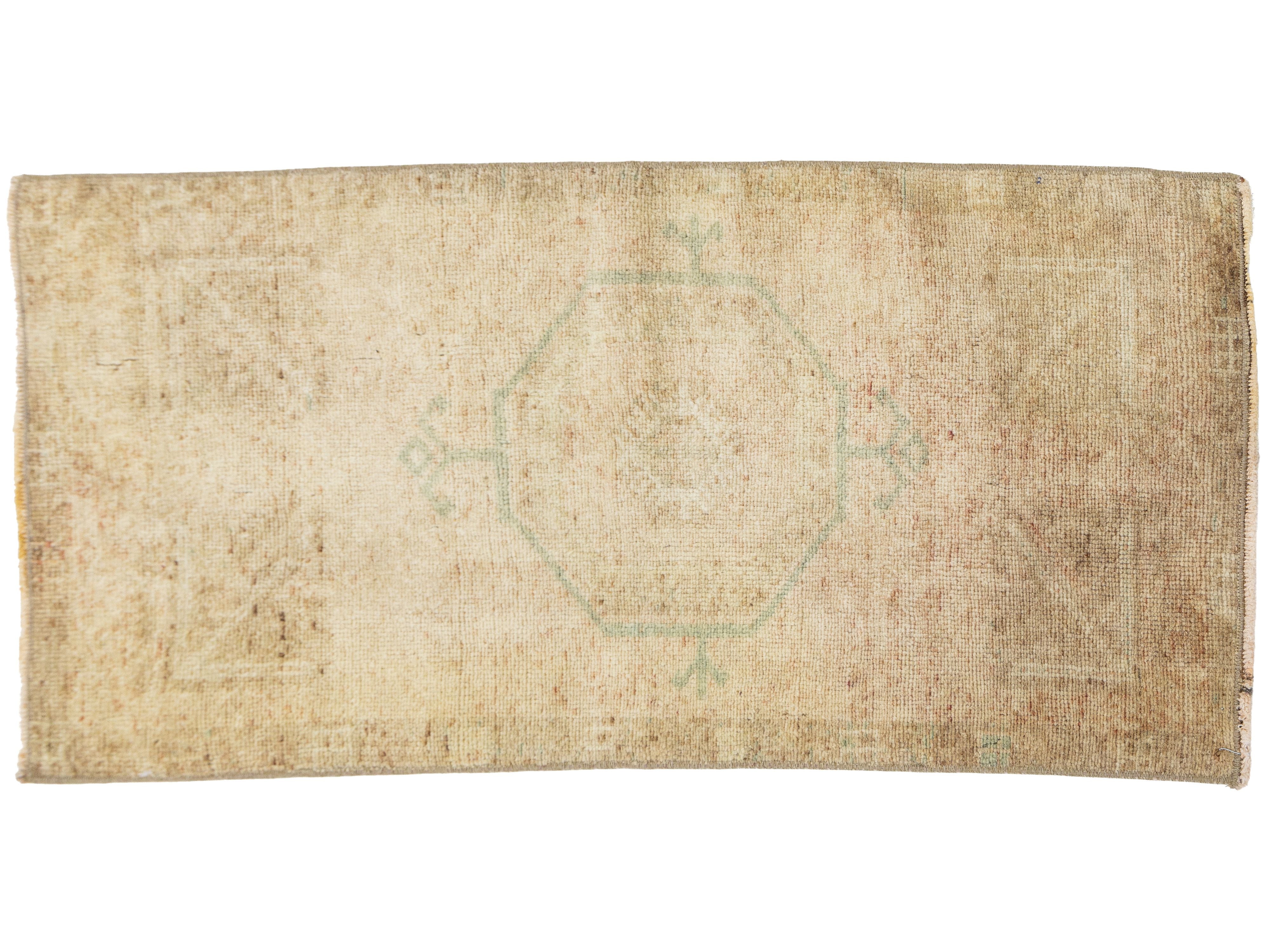 A rectangular vintage-style rug with a distressed, faded appearance. The rug features a muted central octagonal medallion and corner motifs in a pale sage green on a heavily worn, sandy beige background.