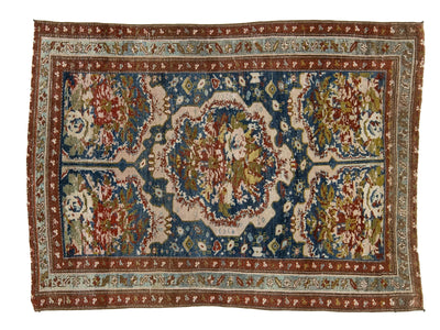 An antique Persian-style wool area rug with a central medallion and intricate floral motifs, featuring a dominant blue field, cream borders, and red and green accents.