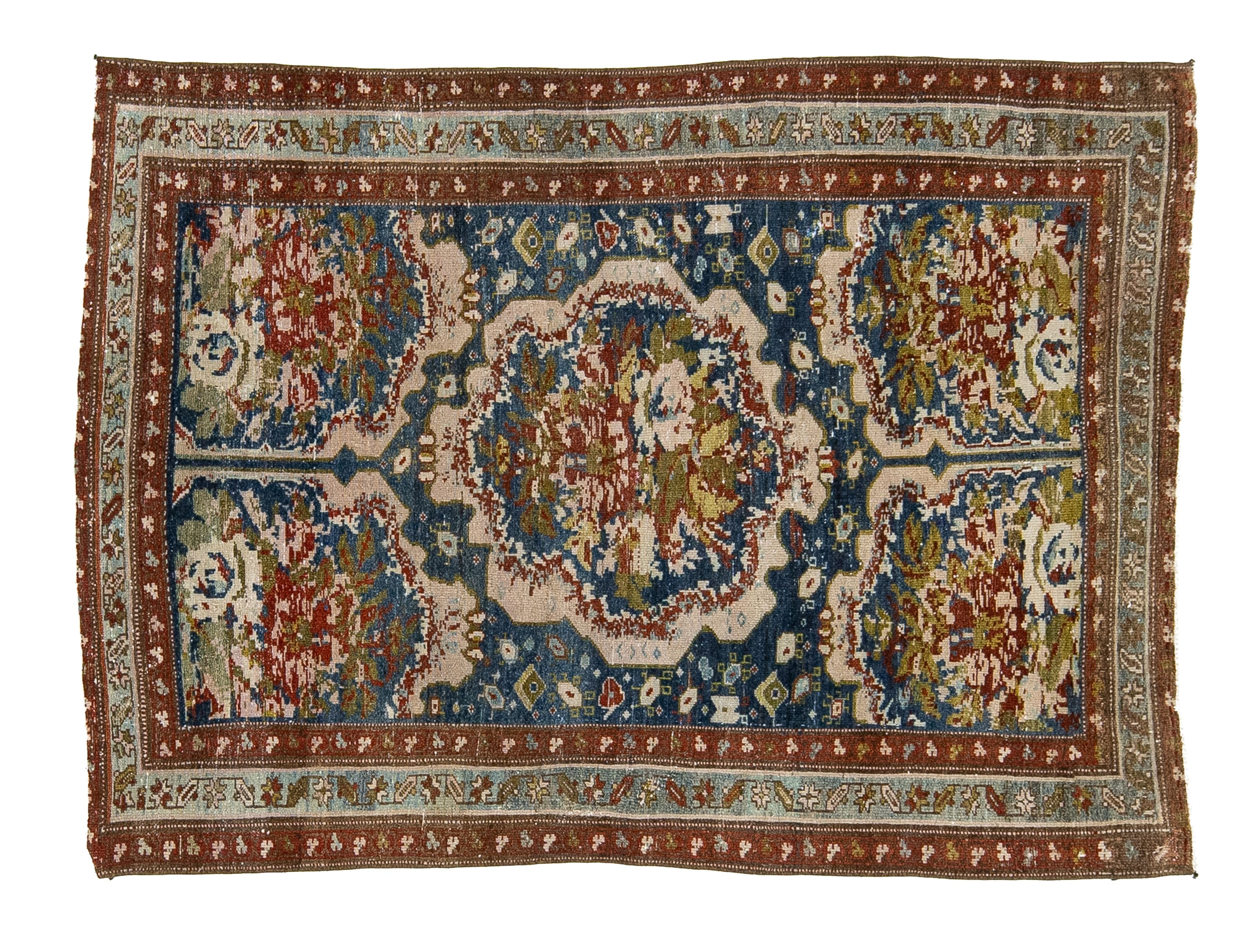 An antique Persian-style wool area rug with a central medallion and intricate floral motifs, featuring a dominant blue field, cream borders, and red and green accents.