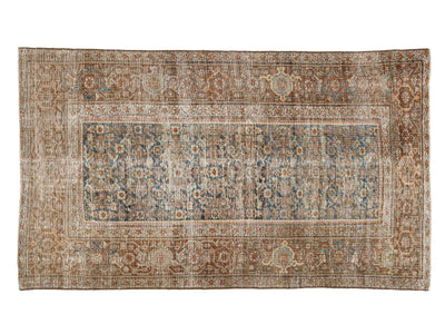A rectangular vintage-style area rug with an intricate traditional pattern, featuring a central field in muted blue-gray tones surrounded by warm beige and brown borders.