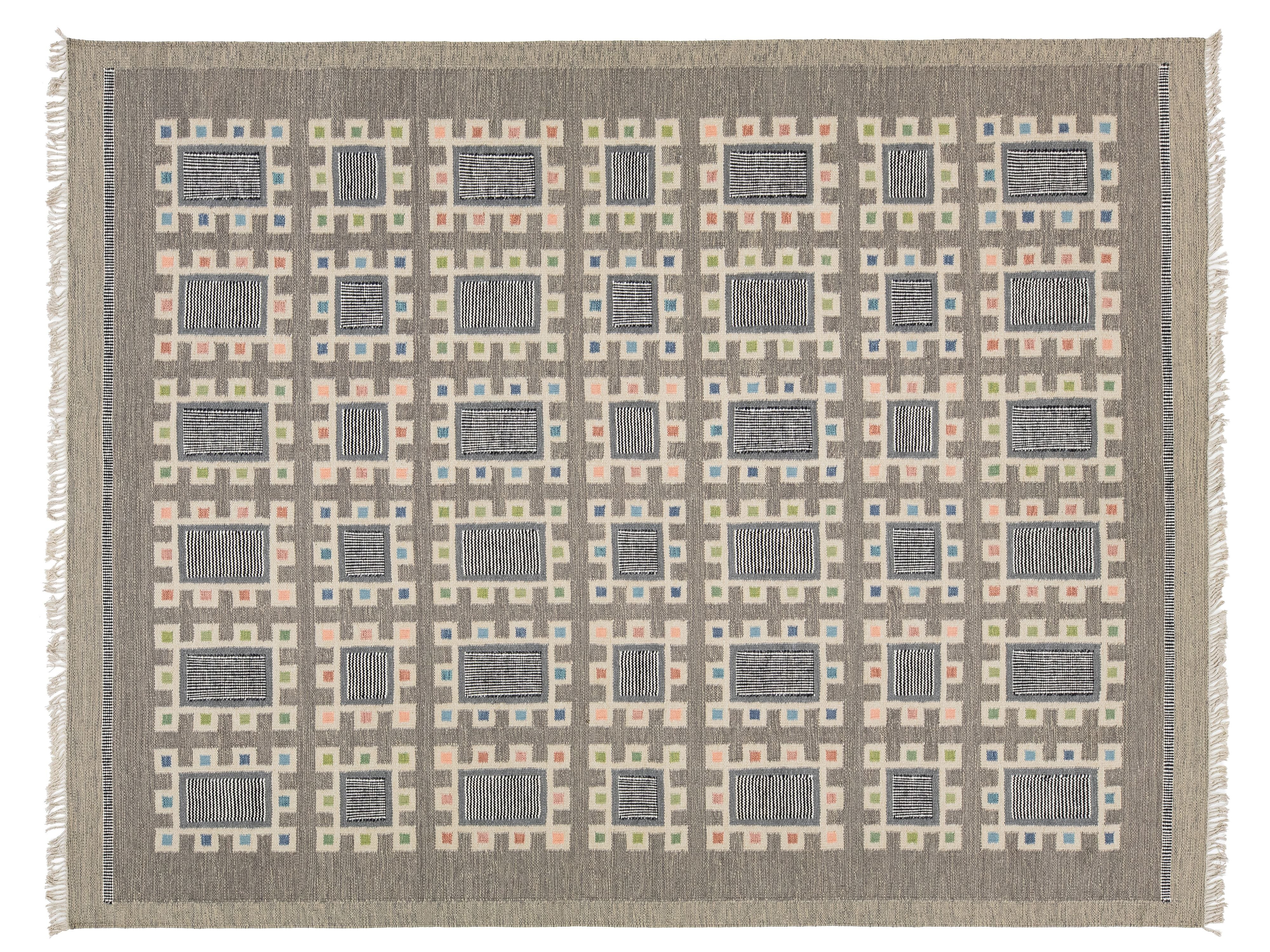 A rectangular woven rug with a geometric grid pattern, featuring alternating dark gray and beige rectangular blocks surrounded by peach, blue, and cream borders. The rug has a taupe-gray border and fringe on the sides.