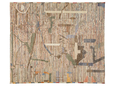 An abstract woven textile or rug featuring vertical striped patterns in beige, brown, and muted blue, with scattered geometric accents in cream, green, orange, and red.